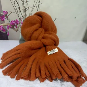 Detail shot of the cozy orange thick knitted scarf showcasing soft woolen texture and delicate fringe.