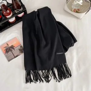 Black cashmere-like winter scarf detail, soft fabric texture with elegant fringes.