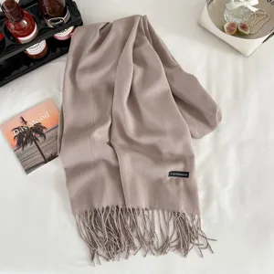 Detailed view of soft beige cashmere feel winter fringed scarf with elegant lifestyle props.