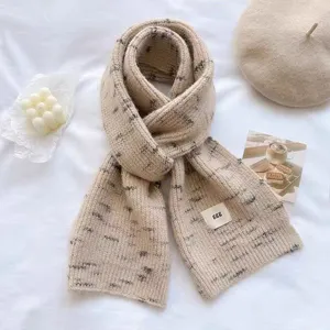 Close-up detail of cozy beige knit winter scarf featuring soft texture and stylish speckled pattern.
