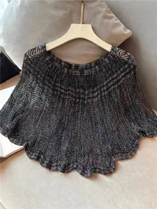 Detailopname toont duidelijk de delicate opengewerkte textuur van de kleurrijke gebreide cape.
