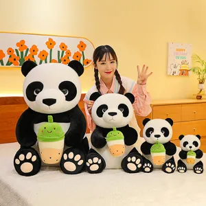 Adorable giant panda plush toys holding cute bubble tea cups in various sizes on bed.