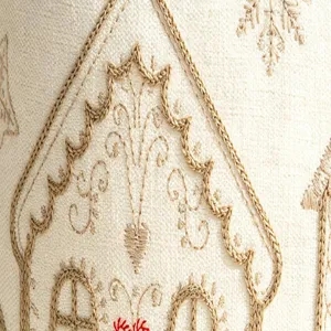 Detailed close-up of beige chenille cushion cover with delicate brown embroidered house motif.
