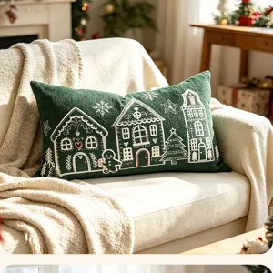 Close-up detail of green chenille Christmas pillow cover with white embroidered houses.