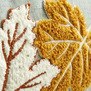 Dettaglio copricuscino ricamato con foglia d'acero ciniglia mostra design autunnale.