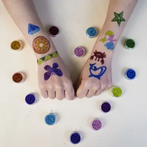 Glitter tattoo kit detail showing colorful body glitter powder and skin art patterns.