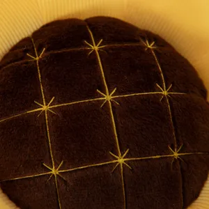 Primo piano del cuscino di peluche girasole, centro marrone morbido con ricami dettagliati.