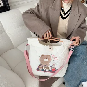Close-up of cream quilted canvas crossbody bag with cute bear embroidery and pink straps.