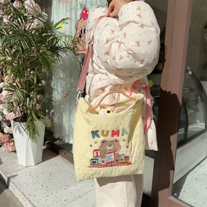 Detailed view of the cream quilted canvas crossbody bag featuring cute Kuma bear embroidery.