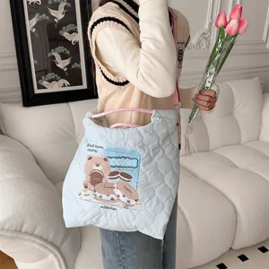 Quilted canvas crossbody bag detail showing cute bear and cookie embroidery design in soft blue.