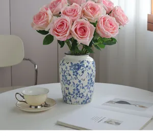 Gedetailleerd overzicht van kunstmatige roze rozen in blauw-witte keramische vaas voor thuisdecor.