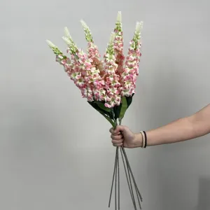 Détail du bouquet de fleurs artificielles avec tiges de fleurs roses et feuilles vertes.