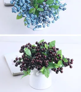 Artificial berry branch detail shot, silk flower plant decor in white ceramic vase for home.