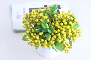 Close-up view of artificial yellow berry branch detail, vibrant fruits and green leaves.