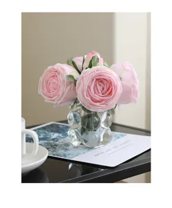 Detailed close-up of artificial pink rose bouquet in clear glass bubble vase for home decor.