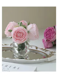 Artificial rose bouquet detail shot, showing soft pink petals and transparent glass bubble vase.
