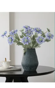 Artificial blue scabiosa flowers bouquet in dark vintage vase for home dining table decor.