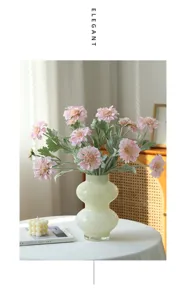 Pink artificial cosmos flower arrangement in light green vase for cozy home decor detail view.