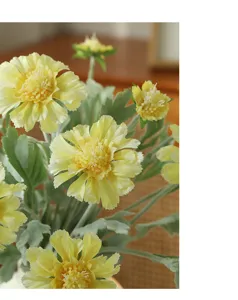 Close-up detail of yellow artificial cosmos flowers with soft flocking texture and green leaves.