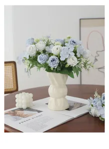 Vue détaillée d'un bouquet de roses artificielles bleu et blanc dans un vase en céramique.