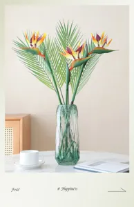 Artificial Bird of Paradise flower detail showing realistic green leaves and elegant glass vase.
