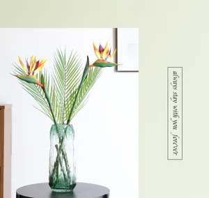 Artificial Bird of Paradise flower arrangement in green glass vase for home decor detail.