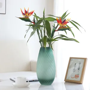 Artificial Bird of Paradise flower arrangement in green glass vase for home decor.