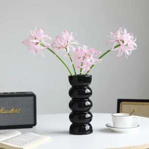 Vaso decorativo nero con bouquet di gigli di mare artificiali rosa per tavolo da soggiorno.