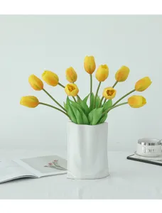 Artificial yellow tulips flower bouquet in white ceramic vase for home indoor decoration.