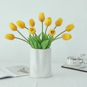Artificial yellow tulips bouquet in white ceramic vase for home indoor decor tabletop display.