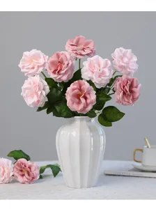 Composizione di fiori di rose rosa artificiali in vaso di ceramica bianca per decorazioni.