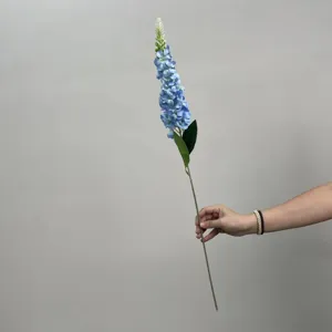 Gros plan détaillé de la tige de fleur artificielle bleue, avec des pétales et des feuilles vertes.