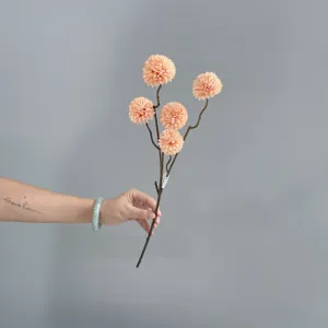 Detailed view of artificial ping pong chrysanthemum branch, pinkish-orange floral decor.