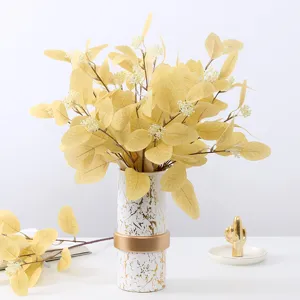 Artificial yellow eucalyptus leaves bouquet with berries in marble vase for home decor.
