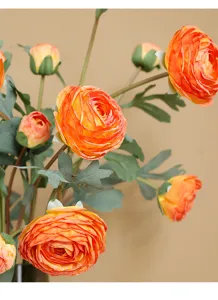 Close-up detail shot of vibrant orange artificial ranunculus silk flowers with green leaves.