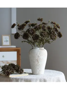 Detailansicht eines künstlichen Wildblumenstraußes in weißer Keramikvase für die Heimdekoration.