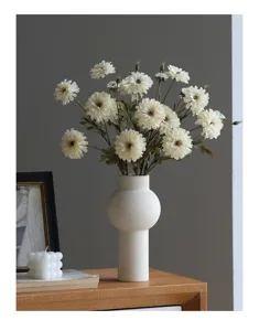 Detailaufnahme künstlicher weißer wilder Chrysanthemen in einer weißen gerippten Keramikvase.
