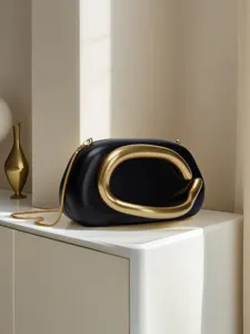Close-up detail of black leather mini handbag with chunky gold hardware and chain strap.