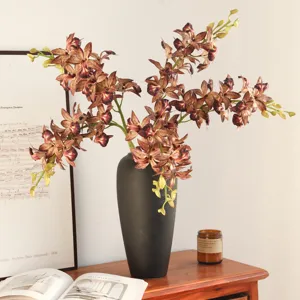 Artificial orchid branch faux Cymbidium flowers in black vase home decor arrangement
