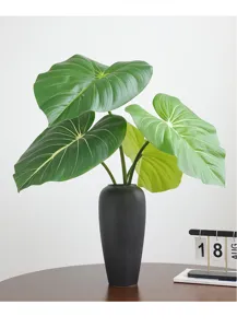 Detail view of artificial monstera and philodendron leaves in a sleek black vase for home decor.
