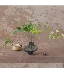 Detail view of artificial green clematis vine branches in grey glass vase, home decor