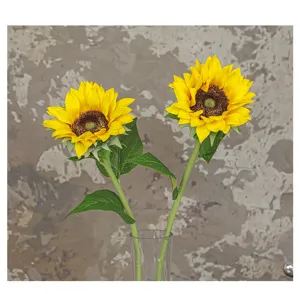 Close-up detail of artificial sunflower flower head, vivid yellow petals and green leaves.