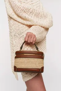 Detalle del bolso vanity tejido en cuero con asa superior y elegante cremallera dorada.