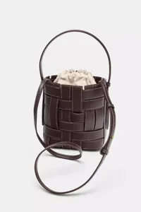 Sac seau en cuir tressé marron foncé avec coutures contrastées, poignée et bandoulière.