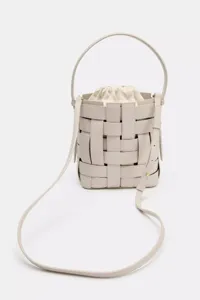 Gros plan du sac seau tissé gris clair, avec poignée supérieure et bandoulière réglable.