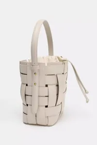 Vue détaillée du sac seau tissé beige clair mettant en valeur son travail de cuir tressé.