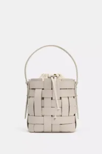 Vue detaillee du sac seau en cuir tresse gris clair avec poignee et cordon de serrage.