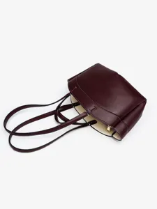 Vue détaillée du élégant sac cabas en cuir bordeaux, mettant en valeur texture et poignées.