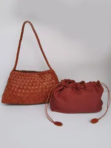 Dettaglio borsa a spalla in pelle intrecciata artigianale con pochette coordinata.