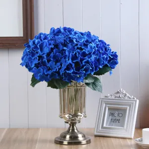 Primo piano di un bouquet di ortensie blu artificiali in un vaso di vetro elegante.